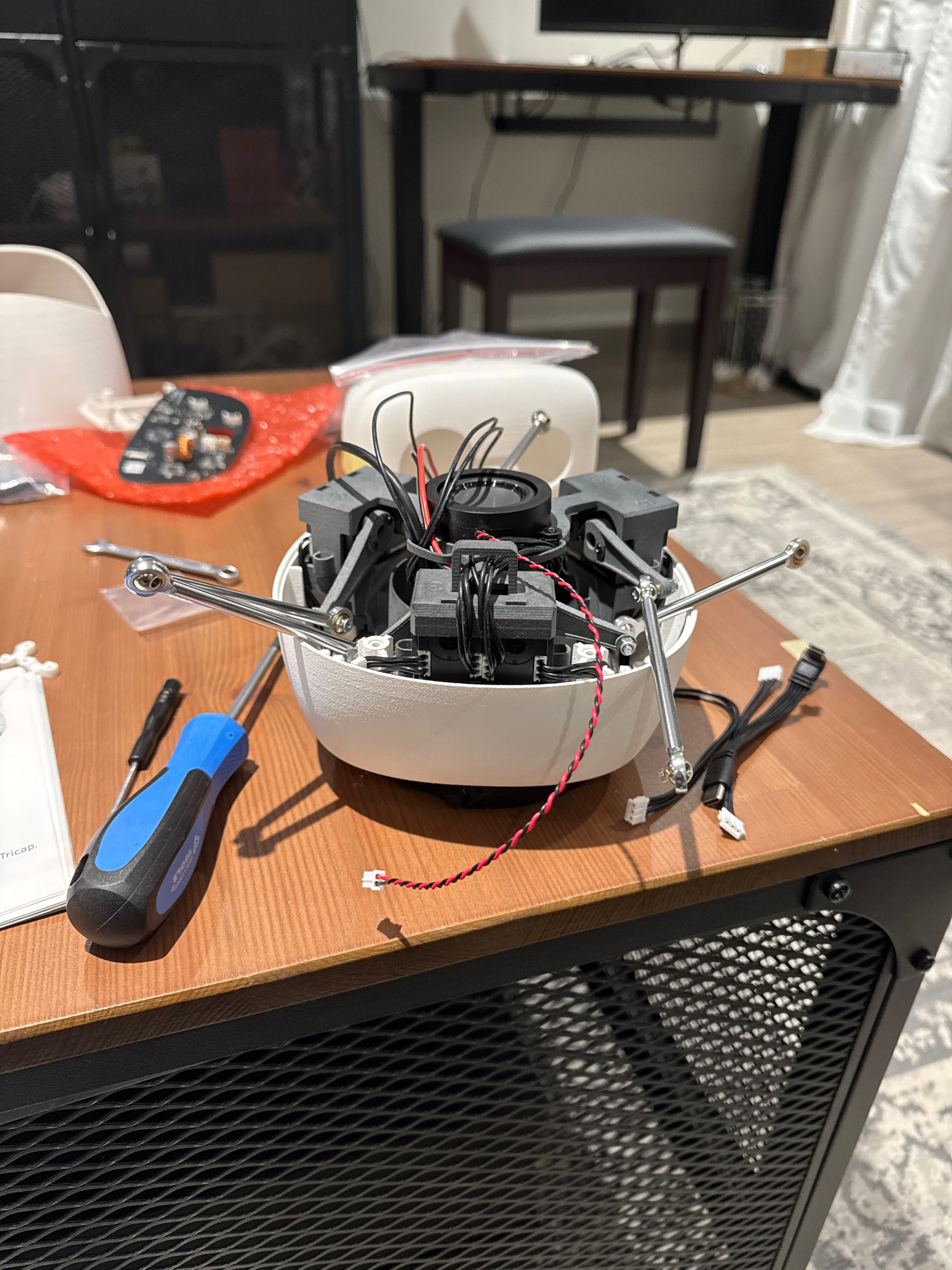 Reachy Mini partly assembled with internal wiring, tools and components visible